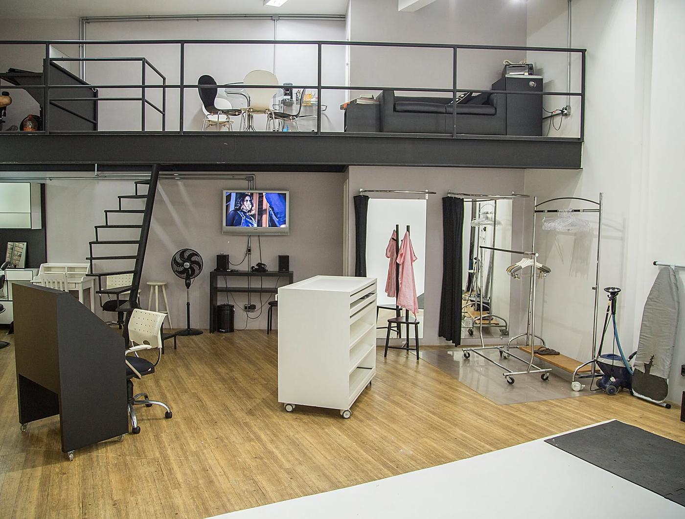 Vista geral do loft com mezanino em estrutura metálica, camarim e piso de madeira